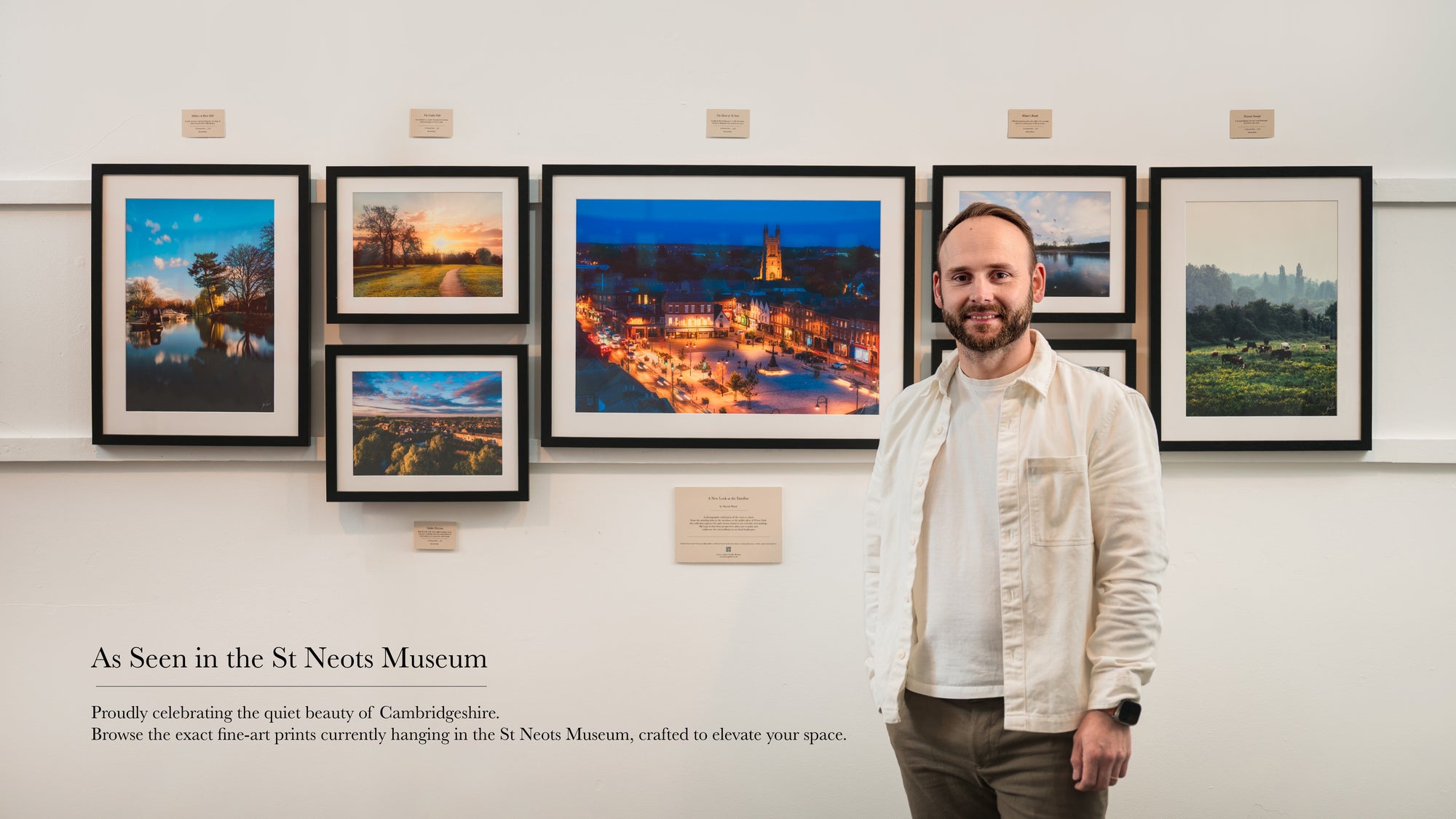 Man standing in front of framed photographs on a wall at St Neots Museum